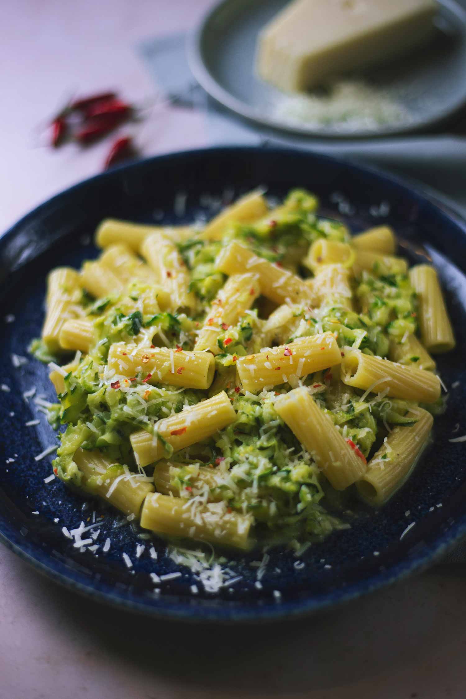 A plate of courgette rigatoni with cheese on top