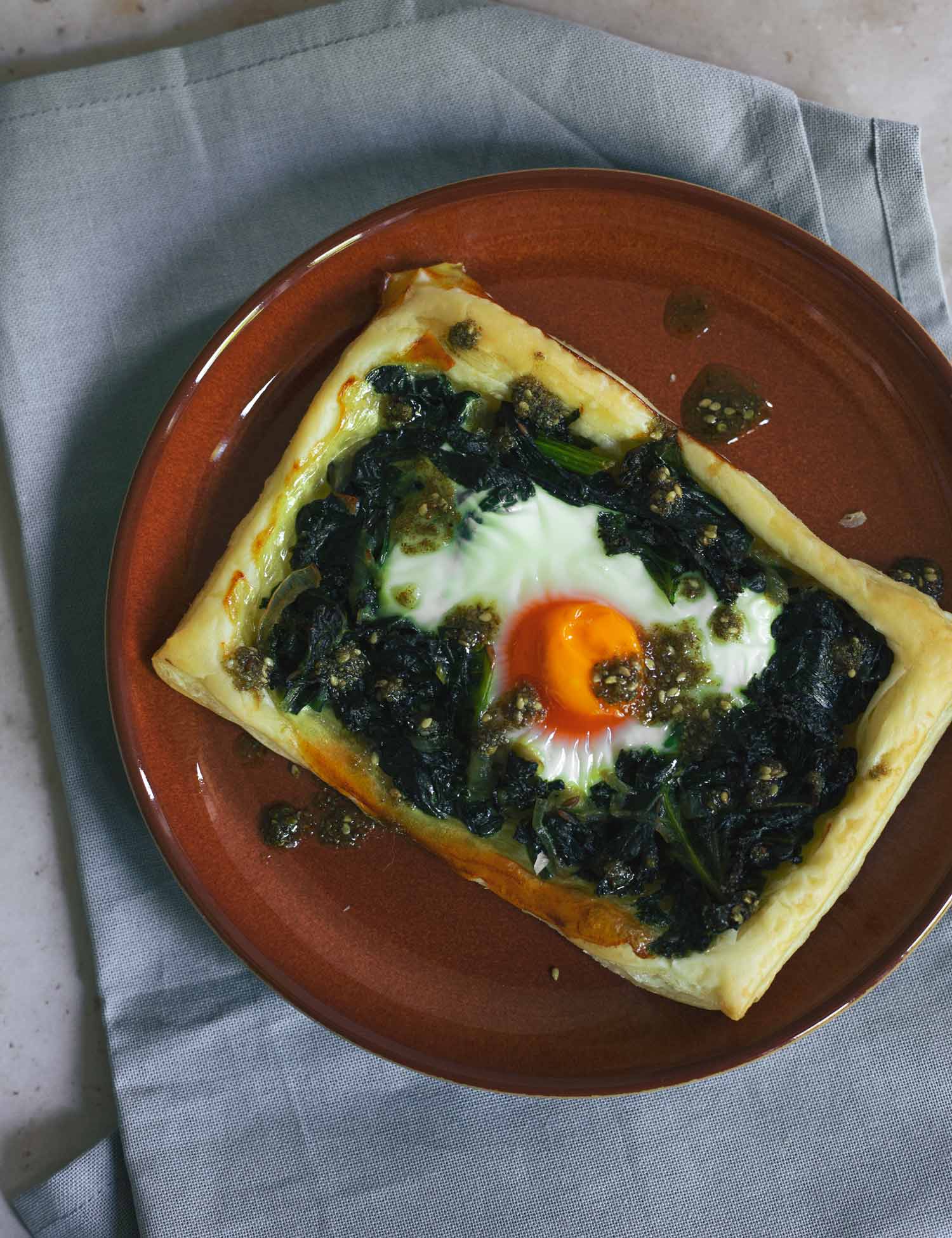 A pastry tart with greens and eggs on a red plate